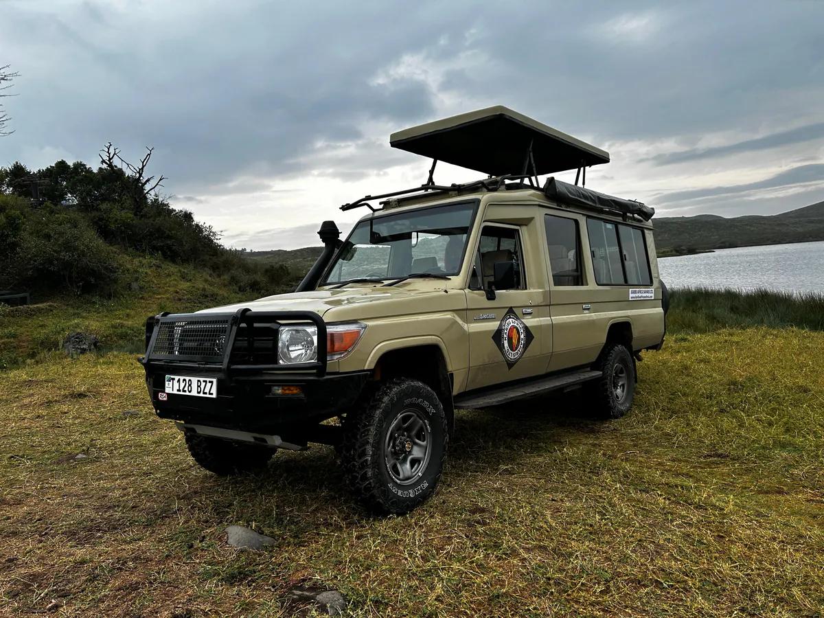 Karibu Africa Safaris Land Cruiser with its pop-up roof raised, parked beside a lake